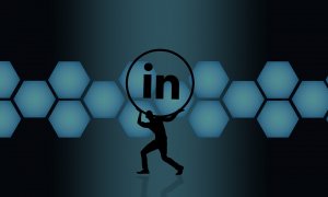 Silhouette of a person lifting a circle with the LinkedIn logo inside, set against a backdrop of interconnected blue hexagons on a dark blue background.