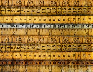 A collection of vintage, weathered measuring tapes with numbers and calibration marks, arranged horizontally in overlapping layers. The resume-length tapes show signs of age, with faded and darkened areas, giving them an antiquated look.