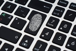 A close-up of a computer keyboard with a unique key featuring a fingerprint symbol highlights data protection. This key replaces the regular key in the same position, standing out among the black keys with white letters and symbols.