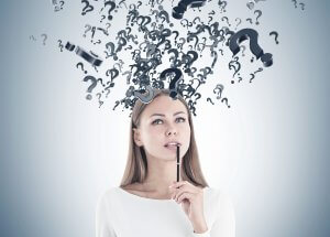 A woman with light brown hair dressed in a white shirt is seen holding a pen to her mouth in a contemplative manner. Above her head are numerous floating black question marks, suggesting deep thought or confusion about employee engagement. The background is a gradient light gray.
