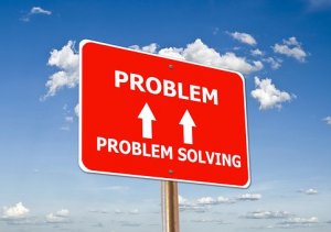 A red sign with white text against a blue sky background reads "PROBLEM" at the top, with an upward arrow below it, and "PROBLEM SOLVING" at the bottom, promoting employee engagement. White clouds are scattered across the sky.