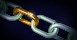 A close-up of a chain with a unique golden link standing out among silver links, displayed against a dark background. The golden link contrasts vividly, symbolizing leadership and highlighting its distinctiveness among the otherwise uniform silver chain.