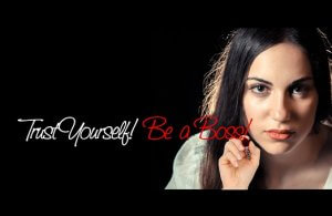 A woman with long dark hair gazes thoughtfully into the camera, radiating confidence and determination. To the left of her, in white and red text, it reads: "Trust Yourself! Raise Your Game! Be a Boss!" The black background makes the text and subject stand out.