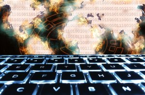 Illuminated keyboard with a digital world map in the background, overlaid with binary code (ones and zeros) and abstract fiery patterns. The image suggests themes of global digital connections, cyber security, and cyber threats.