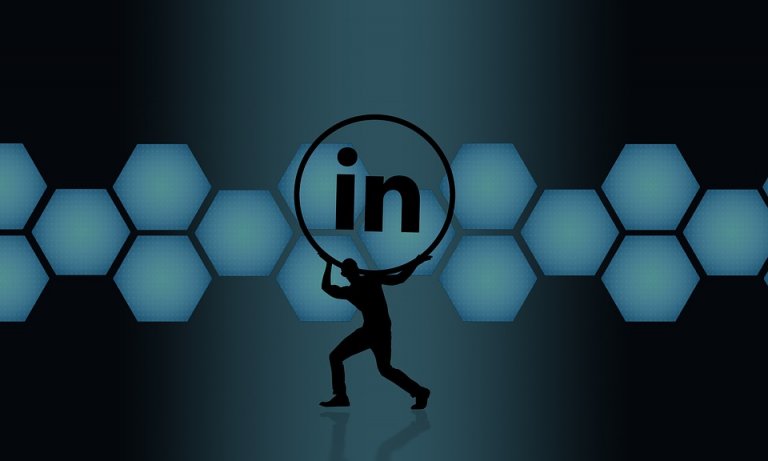 A silhouette of a person is lifting a large LinkedIn logo in front of a background composed of interconnected blue hexagons on a dark gradient backdrop, emphasizing the power of networking.