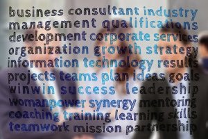 Blurred image of a group of people in business attire standing together, overlaid with various business-related words like "management," "strategy," "ATS," "leadership," "teamwork," and "success" in different sizes and colors.