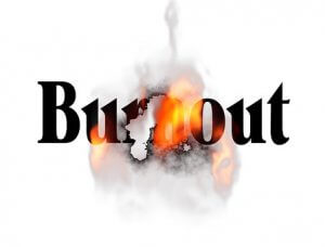 The word "Burnout" is shown with letters partially eroded by flames and smoke, illustrating mid-level leadership feeling overwhelmed and exhausted. The background is white, with the fiery effect providing a stark contrast.