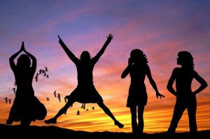 Silhouettes of four people are set against a vibrant sunset sky. One person is jumping with arms outstretched, another has hands in a prayer position, the third exudes leadership with hands on hips, and the fourth appears to be talking on a phone. Birds are flying in the background.
