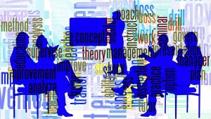 A stylized illustration features five blue silhouettes in a meeting setting, with one person (perhaps your boss) presenting at a whiteboard. Various words related to business, management, and education, such as "analyze," "concept," and "improve," are overlaid in different colors and orientations.