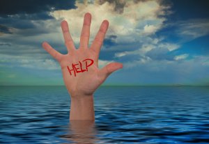 A hand emerges from a body of water, with the word "HELP" written in red on its palm, highlighting the desperate job market against a backdrop of cloudy sky and ocean.
