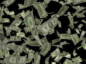 Numerous U.S. dollar bills of various denominations are floating and swirling against a black background, creating the impression of money from a job being thrown or flying through the air.
