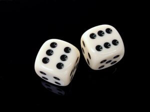 Two white six-sided dice with black dots showing the numbers six and two rest on a glossy black surface, as if waiting for influencers to roll them in a high-stakes game.