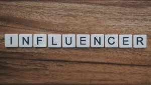 Scrabble tiles spell out the word "INFLUENCER" on a wooden surface, highlighting how influencers shape digital trends.