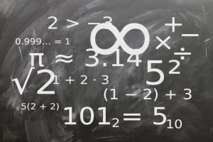 A chalkboard filled with various mathematical formulas and symbols, including an infinity symbol, greater than sign, square root, pi symbol, and several equations like 2>3 and 0.999... = 1. The board is covered with chalk marks—a scene reminiscent of solving complex problems in high-demand IT jobs.