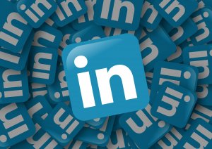 A large LinkedIn logo in white on a blue square is centered and surrounded by numerous smaller logos scattered in the background, creating a 3D effect. The overall theme of blue and white emphasizes a professional atmosphere, reminiscent of a polished resume.