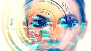 Double exposure image featuring a close-up of a camera lens with aperture and focal length markings overlaying the image of a woman's face and a chessboard. The blending of elements creates a surreal, artistic effect combining photography, strategy, and leadership themes.