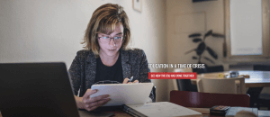 A person wearing glasses sits at a table, using a tablet. A laptop and a notebook with notes are in front of them. Text on the image reads "Education in a Time of Crisis" with a red button below that reads "See How CSU's VLE Has Come Together.