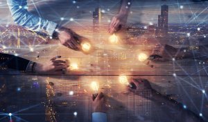 A group of employees sitting at a wooden table with illuminated light bulbs in their hands. The image is overlaid with a cityscape, representing a concept of brainstorming, innovation, or collaborative thinking. Numerous lines and dots suggest connectivity and networks.