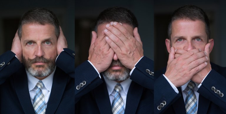 Three-panel image of a man demonstrating the "see no evil, hear no evil, speak no evil" concept. In the first panel, he covers his ears; in the middle panel, he covers his eyes; in the last panel, he covers his mouth. His suit and tie add an air of authority, highlighting how influences can be ignored.