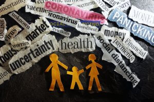 A collage of torn newspaper clippings with words like "coronavirus," "health," "uncertainty," "market," "panic," and "social distancing" paints a stark picture of our world. In the center, paper cutouts of a family with parents and a child hold hands against a dark background.