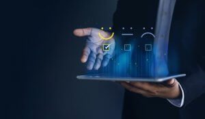 A person in a suit holds a tablet that reveals a holographic interface displaying three feedback icons: a happy face, a neutral face, and a sad face, each with a checkbox underneath. The happy face checkbox is marked, clearly indicating positive feedback.
