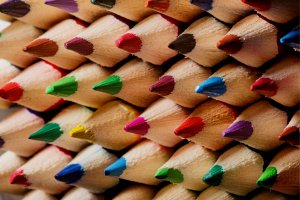 A close-up image of a tightly packed bundle of colored writing pencils. The pencils are arranged with their tips facing outward, displaying a variety of vivid colors including red, green, blue, yellow, purple, and more, forming an eye-catching pattern.