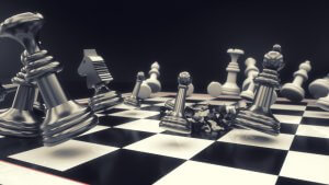 A dramatic scene of a chessboard with scattered chess pieces, some lying on their sides and others mid-fall, indicating an intense moment in the game. The focus is on metallic, glossy pieces against a black and white checkered board, reminiscent of the strategic maneuvers required in Government Jobs, isolated on a black background.