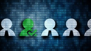 Image of a row of stylized human icons on a digital background of binary code. All icons are white except for one in green holding a heart symbol, likely representing individuality and the unique opportunities in Government Jobs within a technological context.