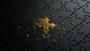 An almost completed black jigsaw puzzle with a single golden piece in the center. The golden piece stands out clearly, surrounded by the fitted black pieces, much like discovering promising careers in government amidst a sea of opportunities, creating a striking contrast.
