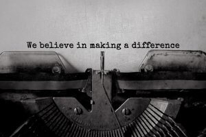 Close-up image of an old typewriter with the text "We believe in making a difference" typed in a simple, vintage font on a textured, off-white background. The typewriter's keys and mechanisms are visible in the foreground, brimming with character and creating a nostalgic atmosphere.