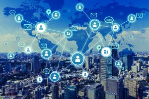 A cityscape overlaid with digital icons connected by lines, depicting a global network. The background shows high-rise buildings under a clear blue sky, while a faint world map highlights the interconnectedness of people, emails, and communication systems—reminiscent of LinkedIn’s professional ecosystem.