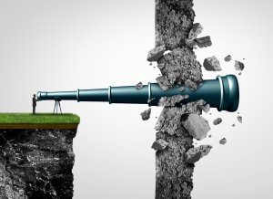 A person stands on the edge of a cliff, looking through a large, extended telescope that pierces through a stone wall, causing it to crack and break apart. The telescope symbolizes how leaders can break through barriers and see beyond obstacles.