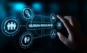 A hand interacts with a digital interface labeled "HR." Surrounding the main label are various icons representing different human resources functions, such as recruitment, employee management, and training, connected by lines in a futuristic, blue-toned design.