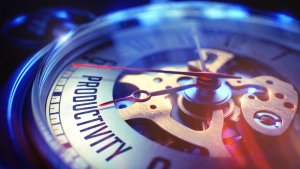 Close-up of a watch's inner mechanisms, highlighting gears and metal components with the word "PRODUCTIVITY" engraved on one of the bridges. Bathed in blue and gold light, the image emphasizes the intricate details of the timepiece's construction.