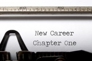 Close-up of a typewriter typing "New Career Chapter One" on white paper. The typewriter's metal ruler is visible at the top, indicating the text's position. The image symbolizes beginning a fresh career journey.