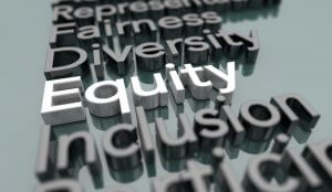 The image shows the words "Fairness," "Diversity," "Equity," "Inclusion," and "Participation." "Equity" is highlighted in bright white while the other words are in darker shades of gray. The 3D text sits on a reflective surface, emphasizing the culture of inclusivity and fairness.