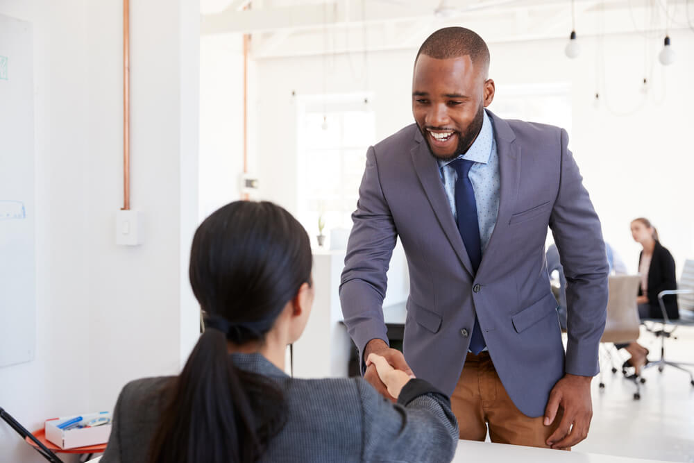 Black,Businessman,And,Seated,Woman,Shaking,Hands,In,Office women's leadership