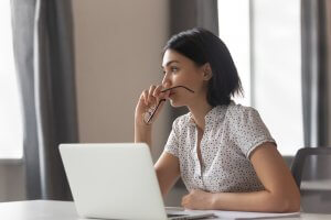 A woman with short black hair sitting in front of her laptop