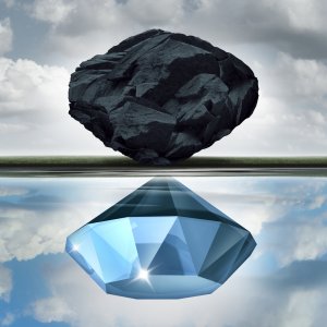 A large, rough, black rock hovers above a calm body of water, reflecting a polished, faceted blue gemstone beneath. The sky is cloudy, crafting a surreal image of transformation and leadership in contrast.