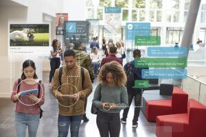 A group of millennials in a bright, modern space appear engaged with their smartphones and tablets. Overlaid digital graphics illustrate their devices' activities, such as text messaging, watching videos, checking the weather, and listening to music.