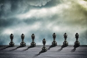 A chess pawn standing in front of other chess pawns