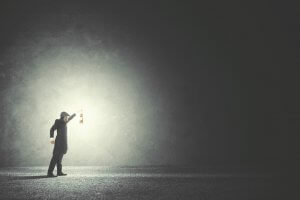 A man holding a lamp and illuminating the darkness