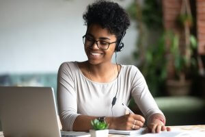 A young woman with headphones on, sitting in front of her laptop