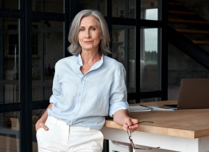 An older woman standing in front of her office desk