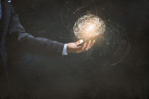A person in a suit extends their hand, holding a glowing, holographic brain surrounded by interconnected lines and symbols, symbolizing technology and innovation in the job search landscape against a dark background.