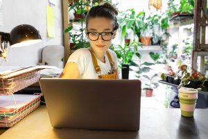 A young woman with glasses sitting in front of her laptop