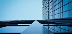 A low-angle shot of a modern glass skyscraper, emphasizing vertical lines and reflections. The facade is made up of numerous reflective windows, giving a towering, infinite appearance against a clear blue sky—perfect for those searching for something special, like government jobs in Texas.