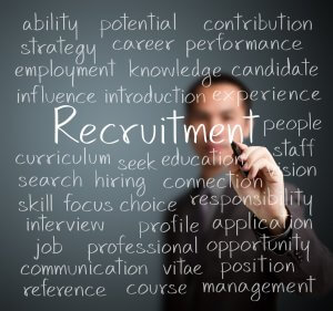 A person writing various words associated with government recruitment on a transparent board. Words include "ability," "potential," "strategy," "career," "performance," "employment," "knowledge," "candidate," "influence," and more.
