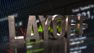 3D metallic letters spelling "LAYOFF" stand prominently against a dark background filled with falling stock market graphs and cascading binary code, capturing the stark reality of job cuts in an economic downturn.