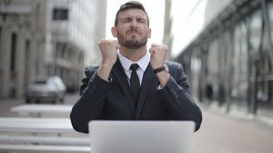 A man in front of laptop jubilating